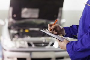 Technician taking notes while standing in front of car 